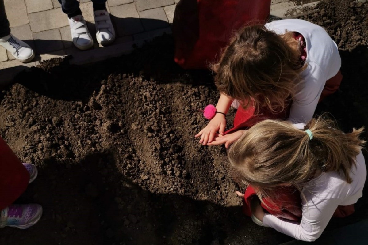 Deca rade sa zemljom u bašti vrtića