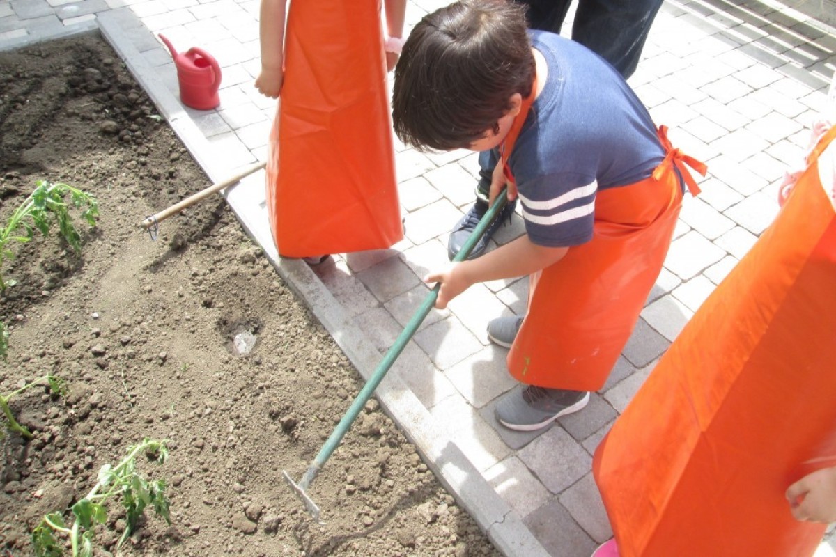 Dečak grabulja baštu vrtića